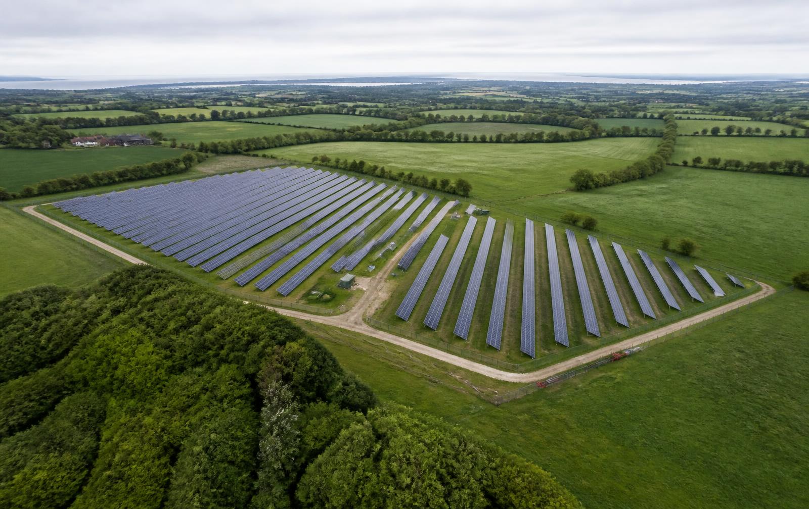Luftfoto af terrænmonteret solcelleanlæg i dansk landbrugsland